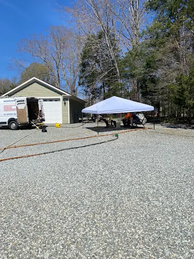 Two Guys job site with canopy, pump pulling rig and service van at a rural home