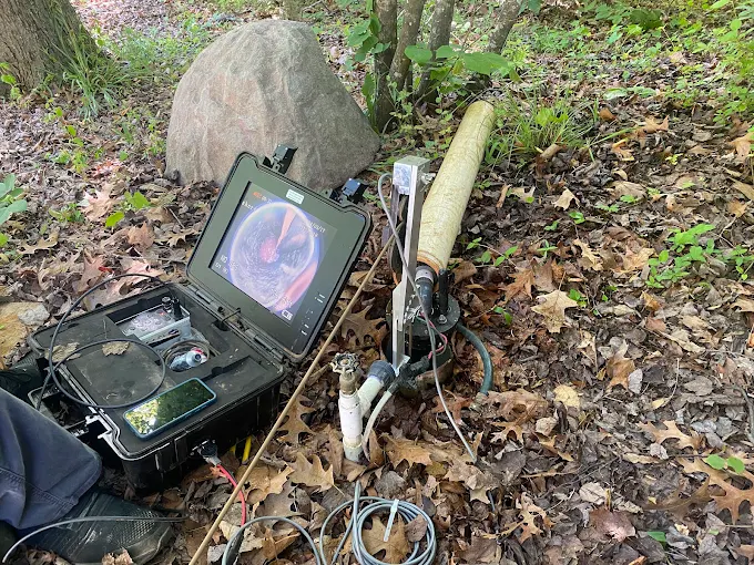 Camera monitor case showing the downhole view at a well head in the woods