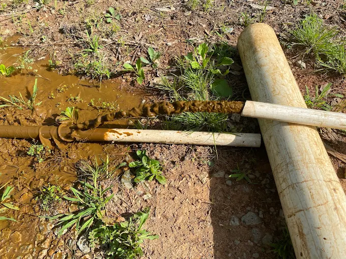 Pulled well pipe caked in heavy iron buildup next to the new replacement