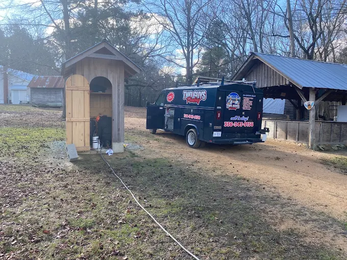Two Guys service van at a wooden well house on a farm property