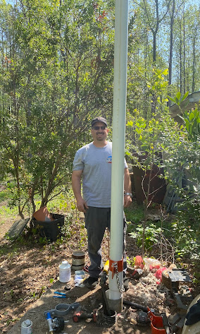 Standing by a freshly installed drop pipe at a well in the woods