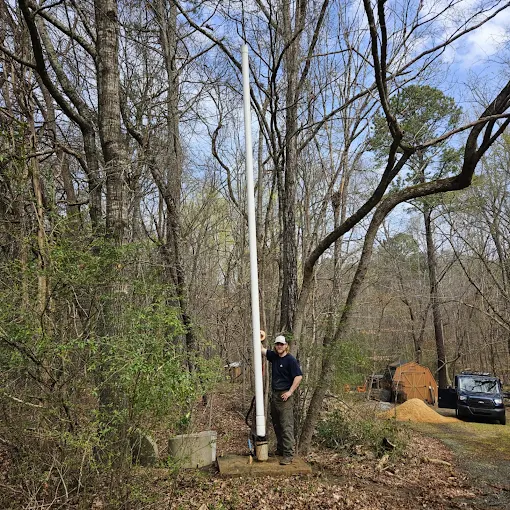 Standing beside a full drop pipe pulled from a deep well in the woods