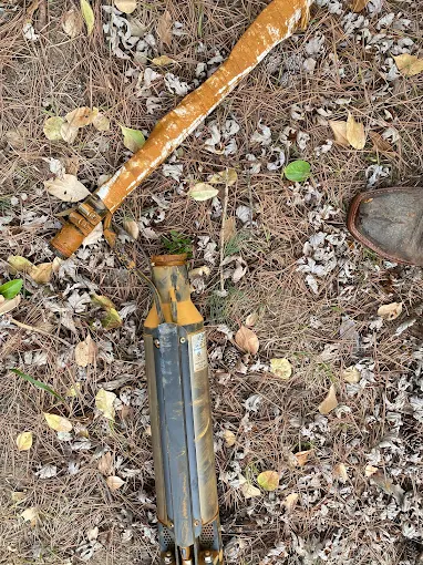 Pulled submersible pump and iron-caked drop pipe on the ground