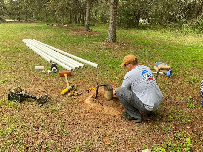 Prepping new drop pipe at a well head with fresh PVC laid out behind