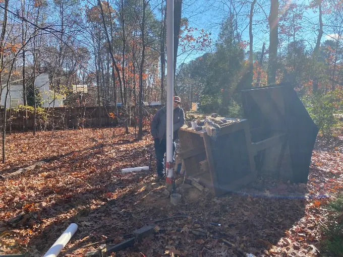 Setting new drop pipe at a well site in a wooded yard