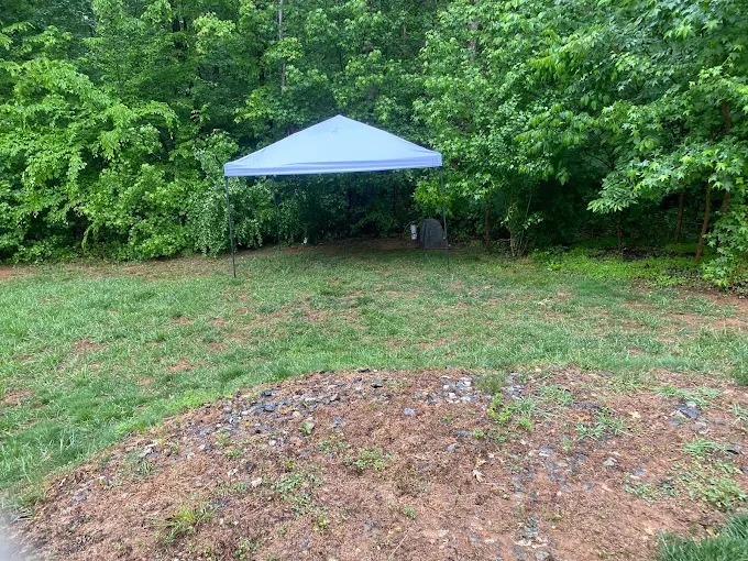 Canopy set up over a well at the edge of a grassy backyard