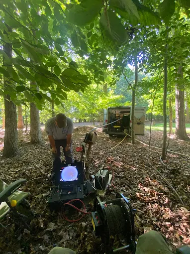 Running a camera inspection at a well head in the woods with the van behind