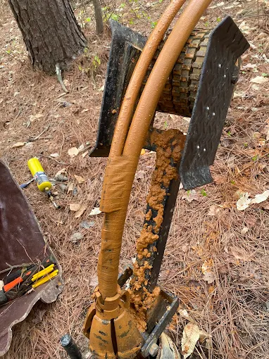 Pulled submersible well pump and drop pipe coated in orange iron buildup