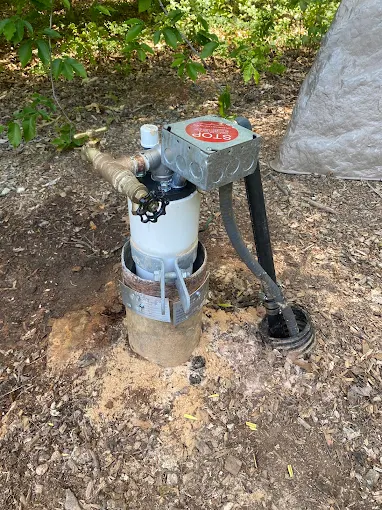 Serviced well head with stop box beside a rock well house cover