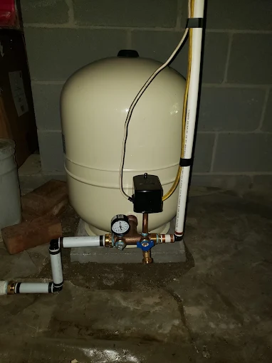 New pressure tank with gauge, switch and fresh piping in a basement