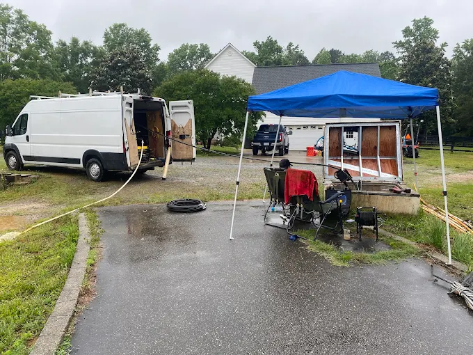 Service van and canopy work station set up at a well house in a driveway