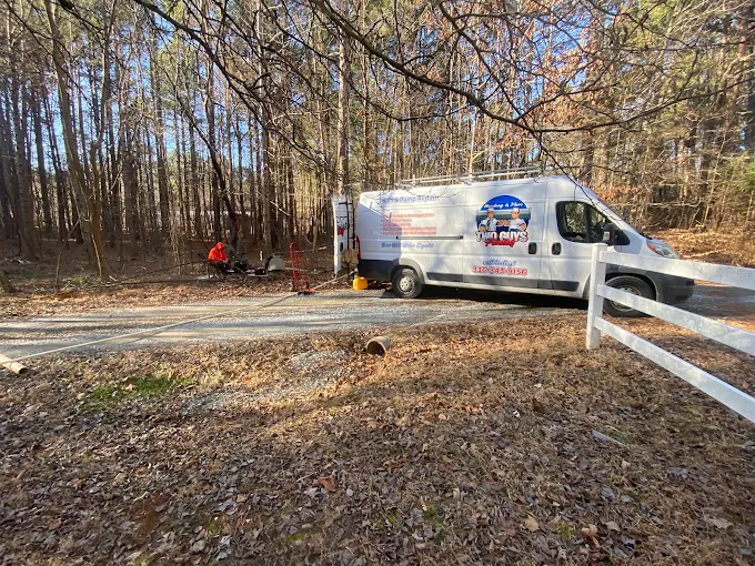 Two Guys service van at a fenced rural property in the woods