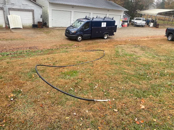 Two Guys service truck on a farm property with a new water line laid across the yard