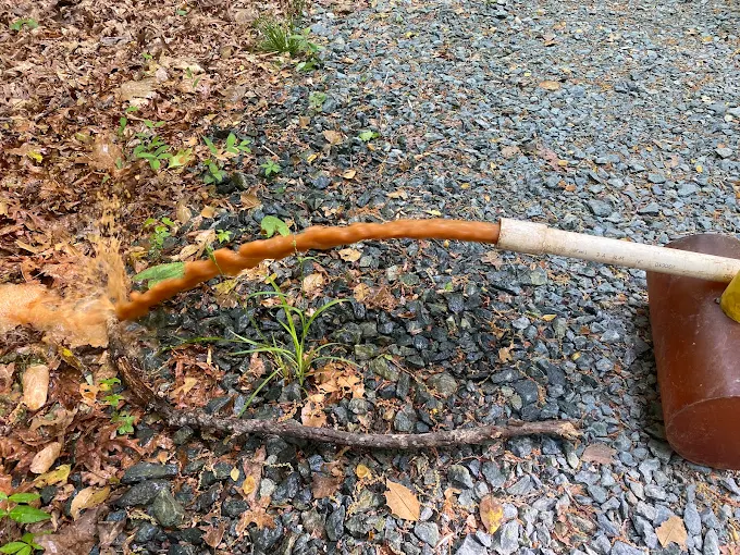 Rusty iron-heavy water flushing from a well line onto the gravel