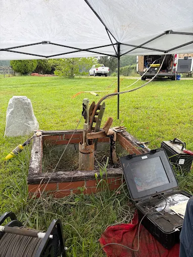 Well camera inspection setup with downhole camera monitor at an open brick well pit