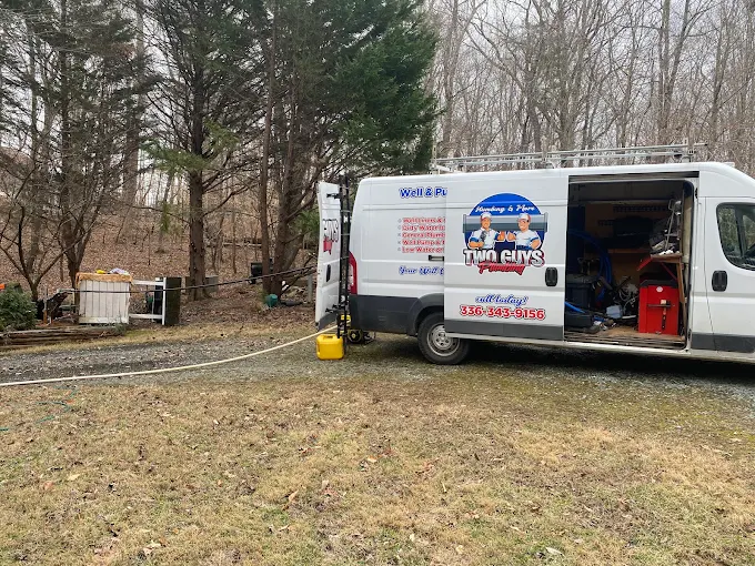 Two Guys service van with doors open and equipment out at a rural well job
