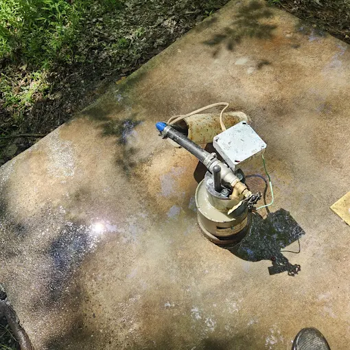 Old galvanized tank and jet pump assembly sitting on a concrete slab