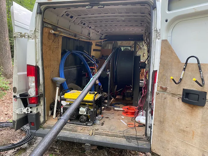 Back of the Two Guys service van loaded with pump hoist, cable reels and tools
