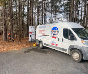Two Guys service van parked on a gravel driveway at a wooded rural property