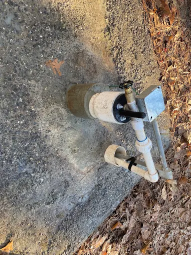 Well casing with fresh PVC plumbing and fittings at ground level