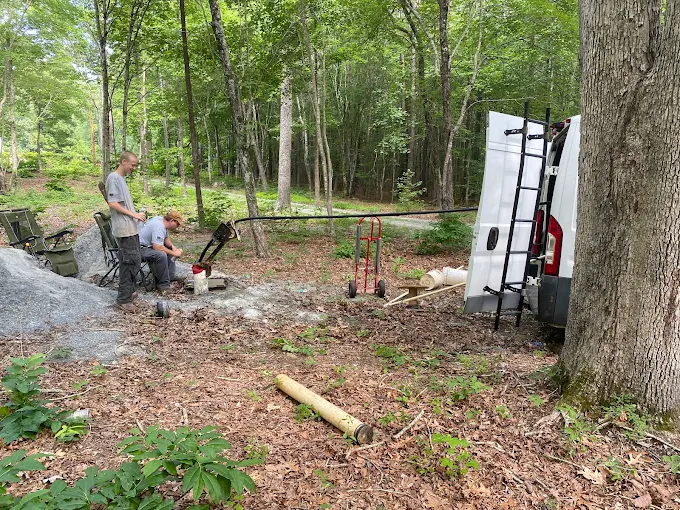 Shane and Joey pulling poly pipe at a well deep in the woods with the service van