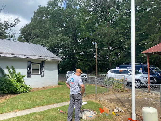 Shane in a Two Guys shirt working a well job beside a country home