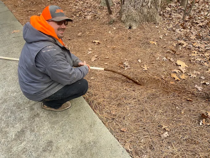 Shane flushing iron-colored water from a well line at the edge of a driveway