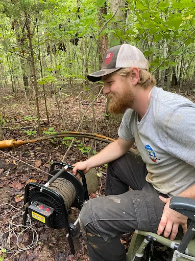 Joey running the camera reel at a well inspection in the woods