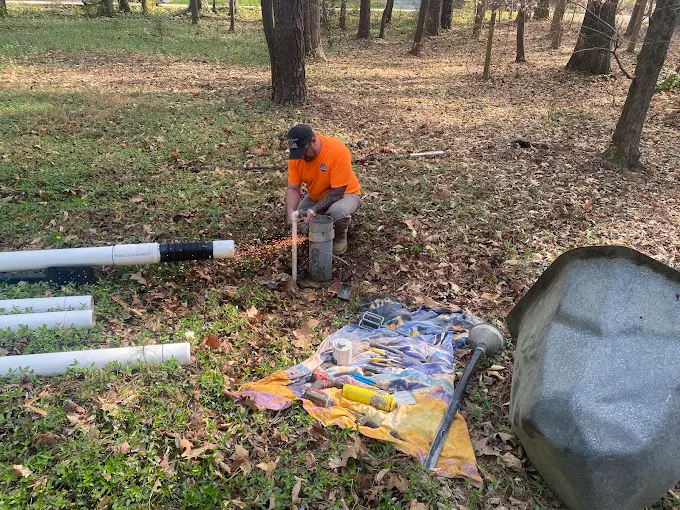 Working on a well head with tools laid out and new pipe staged nearby