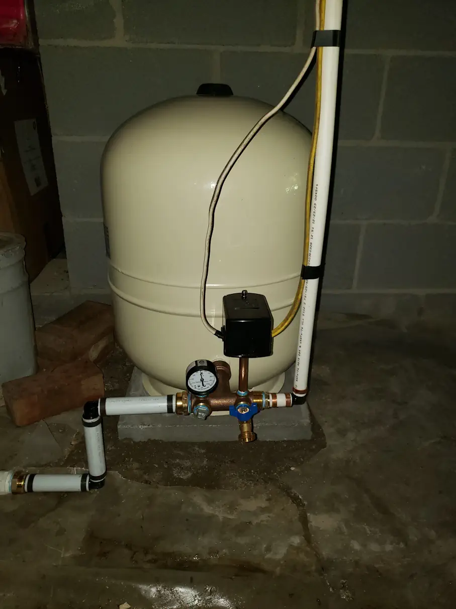 New well pressure tank installed with tank tee, gauge and pressure switch in a basement