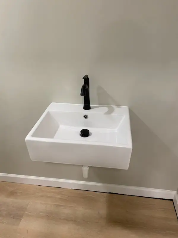 Wall-mount bathroom vanity sink with a matte black faucet installed by Two Guys